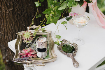 Botanic bridal chic. Bouquet with silk ribbons and greenery, mirror, succulents, wedding rings and engagement ring on vintage table.