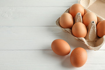 Brown chicken eggs in carton box on white background, space for text