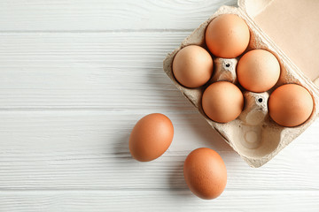 Brown chicken eggs in carton box on white background, space for text and top view