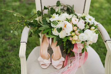Bridal fashion. Pink shoes and wedding bouquet on a vintage chair.