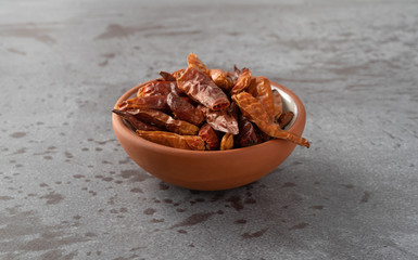 Bowl filled with dried Vietnamese chili peppers on a gray background side view