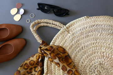 Fashionable accessories: sunglasses, straw bag with leopard print scarf, vintage brown leather...