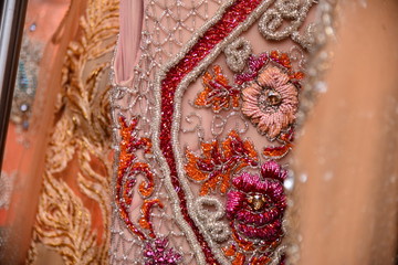embroidered fabric with rhinestones and beads in shades of pink and salmon, background, peach fuzz 