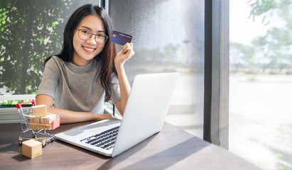 Young woman holding credit card and using laptop computer. Businesswoman or entrepreneur working. Online shopping, E-commerce. Internet banking, Spending money concept