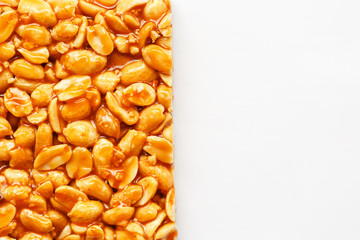A large tile of roasted peanuts bar in a sweet molasses on a white background. Kozinaki useful and...