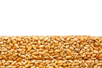 A large golden tile of sunflower seeds, a bar in a sweet molasses on a white background. Kozinaki...