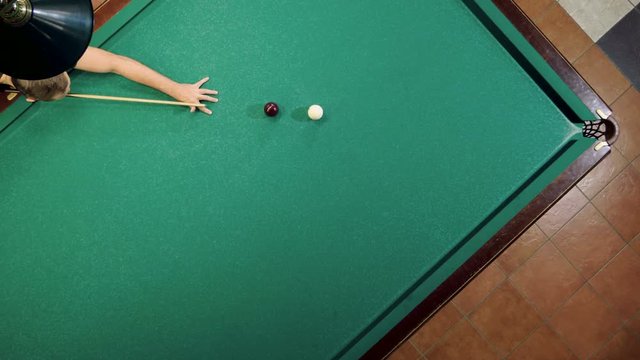 Top view of man playing billiards, hitting the balls with a cue into pockets on a billiard table. 4K