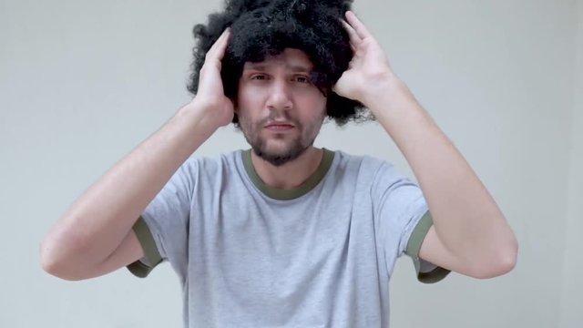 Young man in wig. Close up portrait of afro curly hair man with wig