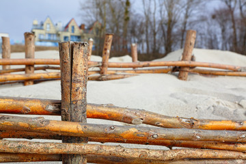 Wooden fence on the beach. White sand and wooden fence. Sand dune reinforcement. Beautiful natural landscape. Baltic coast. Color fence made of logs