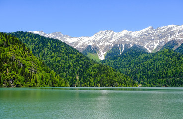 View of lake Ritsa (Riza) in Abkhazia in the spring, in the background snow-capped mountains 