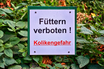Sign with inscription. - Letters with Füttern verboten! Kolikengefahr Means Feeding prohibited!...
