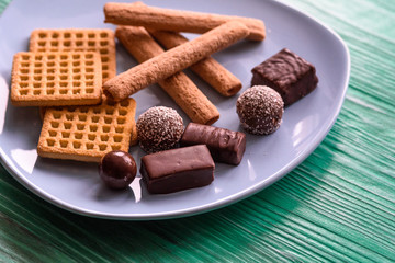 Homemade pastries and chocolates on a ceramic plate on a wooden background.