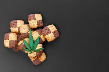 Hemp biscuits on a dark background with a green leaf of cannabis. Marijuana CBD dessert. Copy space. View from above