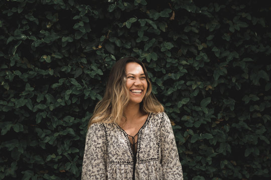 Mixed Race Smiling Woman Standing In Front Plant 