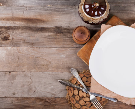 Light empty plate with kitchen accessories on a wooden background in vintage style. View from above