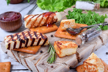 Grilled adyghe cheese, crackers, red jam, spices and cress salad on the wooden board against the white background