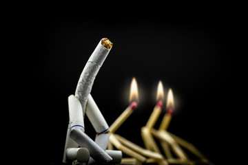 image of a character made of cigarette, alone and sad with black background. Concept of addiction...