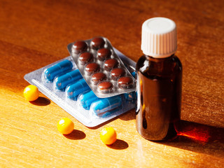 Pills, capsules and pharmacy vials on a wooden table. Medicines and drugs concept.