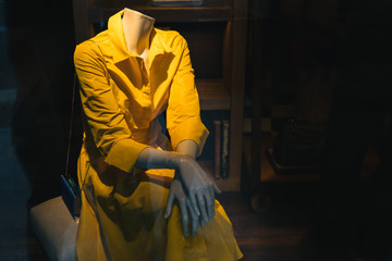 Sitting manikin in yellow dress on the display.