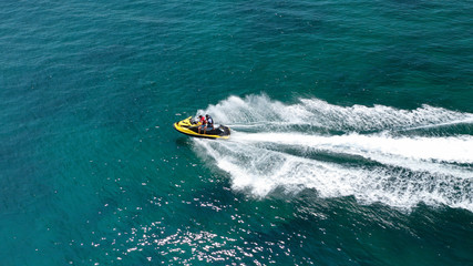 Obraz premium Aerial drone top view photo of jet ski cruising in high speed in emerald exotic tropical bay