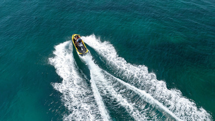 Fototapeta premium Aerial drone top view photo of jet ski cruising in high speed in emerald exotic tropical bay
