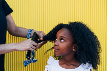Mother doing daughter's afro hair