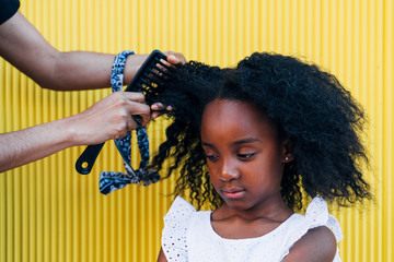 Mother doing daughter's afro hair