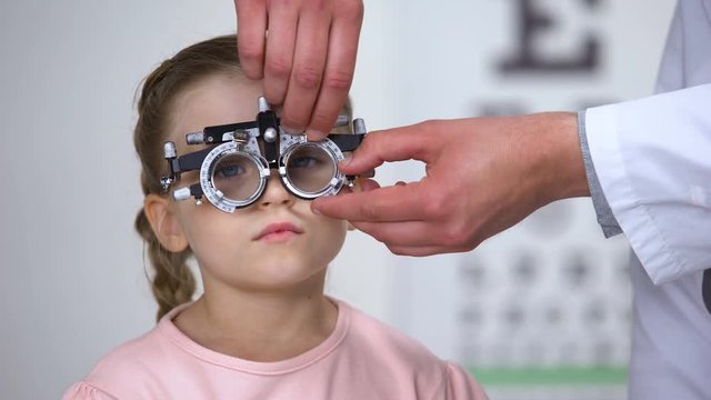 Child saying no and doctor changing lens in phoropter looking for proper diopter