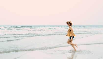Fototapeta premium Woman enjoying beach relaxing joyful in summer by tropical blue water.Model on travel wearing beach hat.