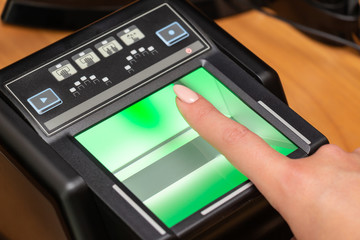 The process of scanning fingerprints during the check at border crossing. Female hand puts fingers to the fingerprint scanner. Biometric, identity verification and border control, immigration concept