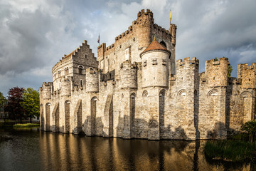 Fototapeta na wymiar Fortified walls and towers of Gravensteen medieval castle with moat in the foreground, Ghent East Flanders, Belgium