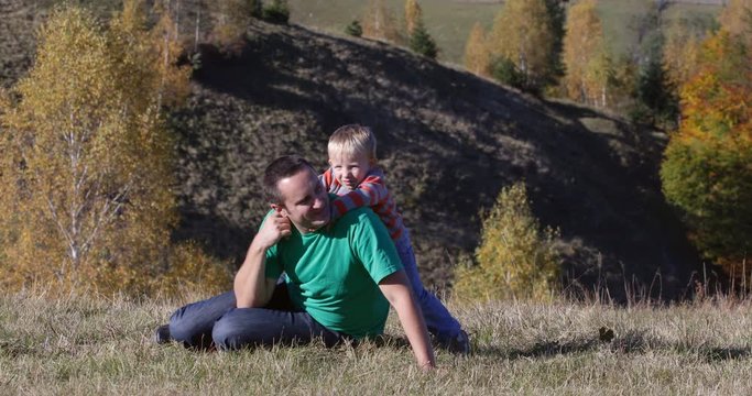 Lovely child embrace and play with father, happy moments in autumn nature
