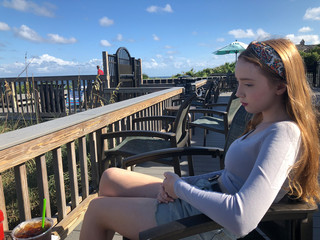 Contemplative teenager gilt sitting at the beach cafe