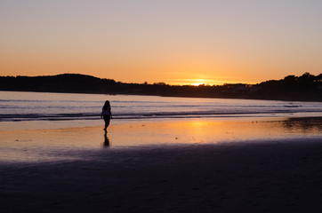 Fototapeta na wymiar Woman walking at sunset on the beach of La Lanzada, O Grove, Pontevedra, Galicia, Spain. No people.