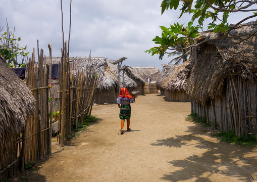 Panama, San Blas Islands, Mamitupu, Kuna Woman Passing In Front Traditional Houses With A Solar Panel