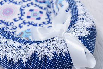 Mattress cocoon for newborns. Bedding for a baby cot. Blue mattress decorated with ribbons and lace.