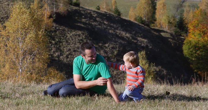 Little son kissing young father in nature, autumn forest