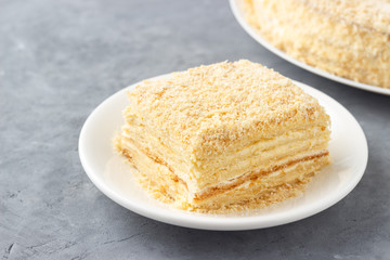 Layered cake with cream Napoleon millefeuille vanilla slice on a white plate.
