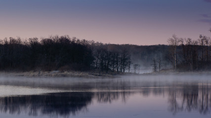 Sunrise lake and sky mirrored images, Calm as glass lake water reflecting the sky above, misty water