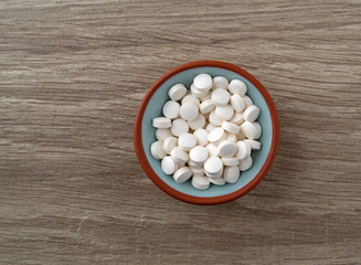 Fototapeta na wymiar DHEA pills in a bowl on a table top view