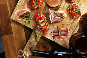 antipasto various appetizer. Cutting board with prosciutto, salami, cheese, bread and olives on dark wooden background