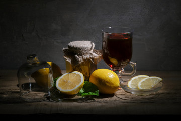 Fresh lemons, a jar of honey and a glass of tea on the table.