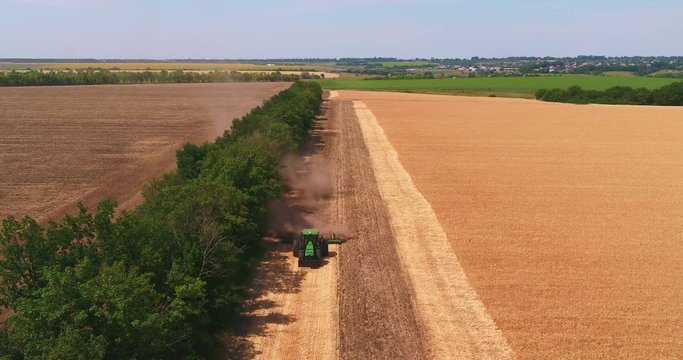 A tractor is poughing the field up after gathering in wheat 2
