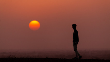 Man standing besides the sun during sunset