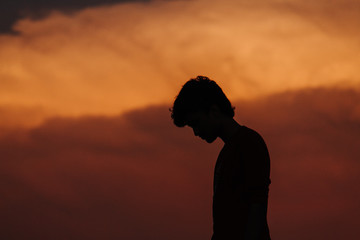 Silhouette of man standing in front of dramatic orange sky during sunset