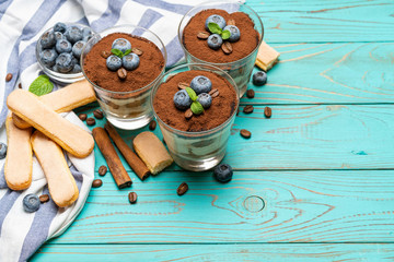 Classic tiramisu dessert in a glass with blueberries on blue wooden background
