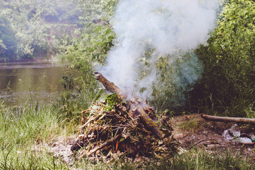 A fire is burned on the ground, and thick smoke rises to the top.
