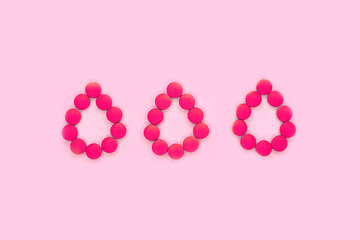 Women's periods medical concept made of tablets or pills in the shape of blood drops on pastel pink background.