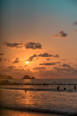 Silhouette of seagulls resting on the remains of a pier on the beach.