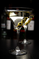 Martini drinks with olives in bar on black table